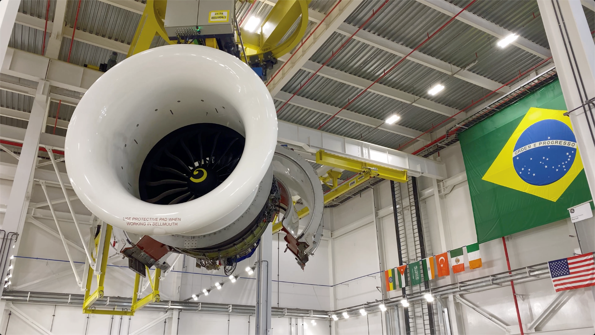 LEAP engine hanging in the air in a warehouse with a Brazil flag in the corner